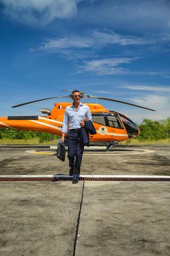 A sharp low angle shot of a clean white luxury helicopter tail rotor parked on a secure concrete helipad in Phuket under a clear blue sky highlighting advanced aviation infrastructure and corporate travel precision